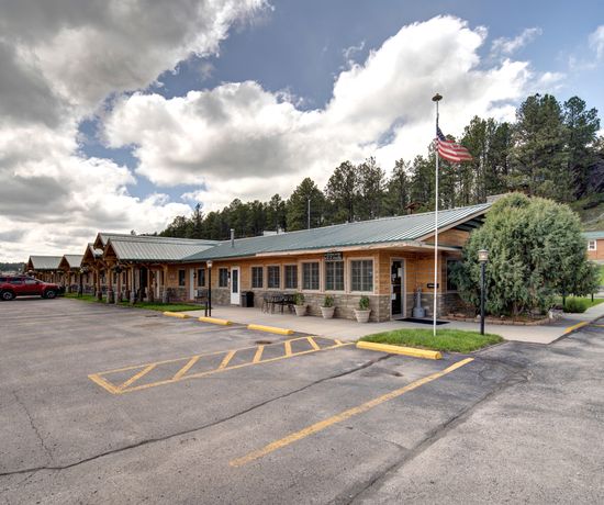 Exterior of the lodge and parking lot. There is a sign on the right side of the building that says "Office". An American flag waves in front of the building.
